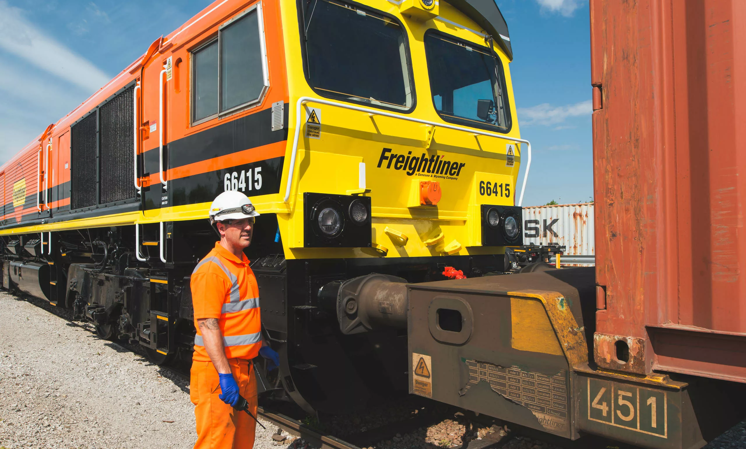 Freightliner employee working on class 66 loco in terminal.