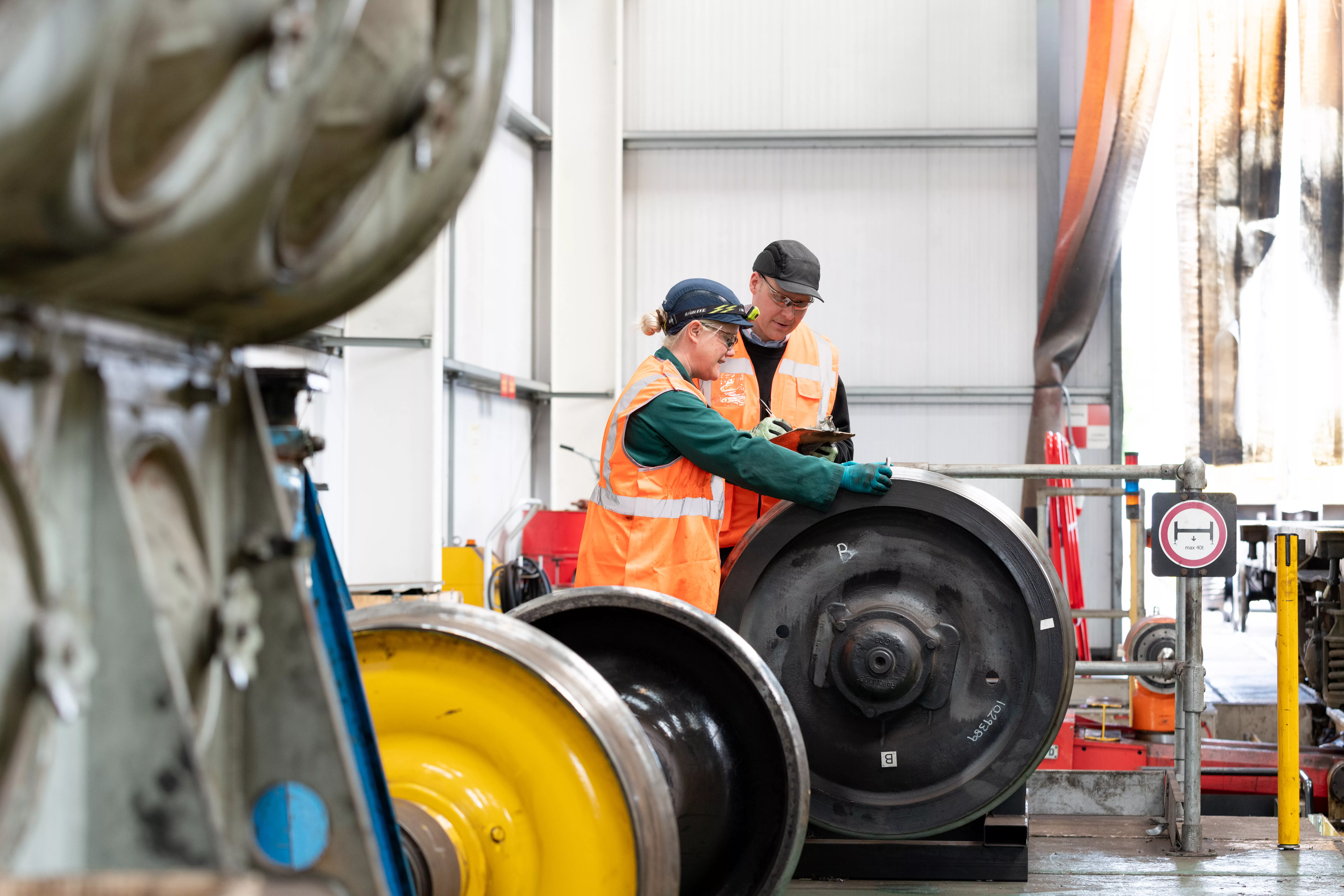 Freightliner employees performing safety checks on train wheels.